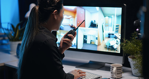 woman monitoring security cameras using a radio in a modern office environment reviewing multiple camera feeds showing various sections of a building related to 11 important areas of security