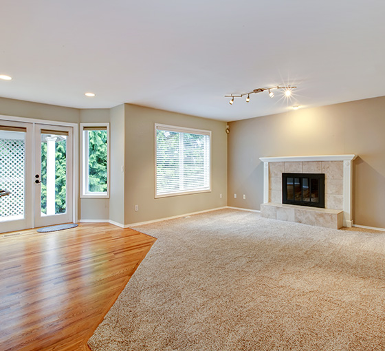 spacious living room with hardwood flooring and large windows featuring a cozy fireplace perfect for relaxing and family gatherings