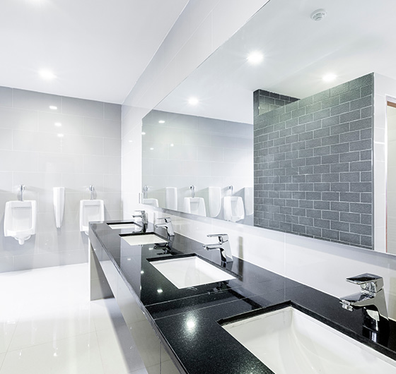 modern restroom with two sinks and two urinals featuring sleek finishes and bright lighting