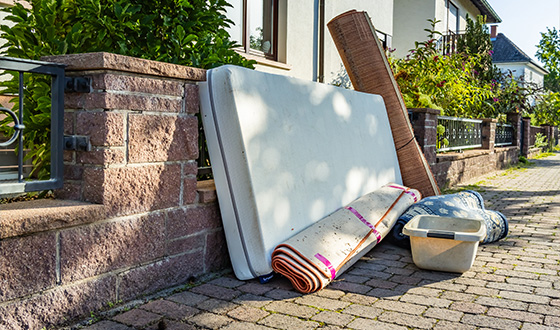 discarded furniture including mattress rolled carpet and container outside residential area 4 items for disposal