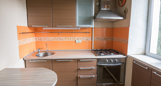 modern kitchen with orange accents featuring a sink gas stove and cabinetry perfect for two cooking adventures